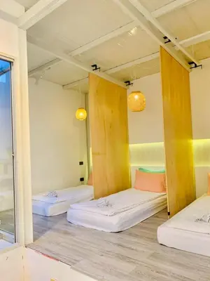 a room with three beds and a mirror at Loft Rattanakosin Mansion in Bangkok