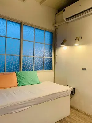 a bedroom with a bed and two large windows at Loft Rattanakosin Mansion in Bangkok