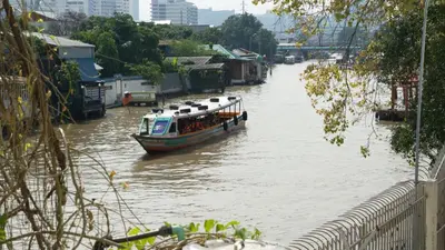 a boat traveling down a river with buildings on it at Bangluang Boutique Hotel in Bangkok