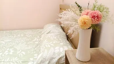 a vase with flowers on a table next to a bed at Rhythm of love in Bangkok