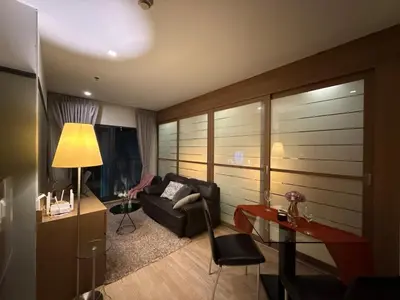 a living room with a couch and a table at Noble Remix Thong Lo Long Stay Cozy&Warm Direct access to BTS Pool Gym WiFi in Bangkok