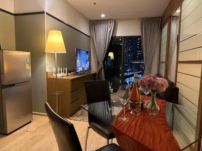 a room with a table with wine bottles and flowers on it at Noble Remix Thong Lo Long Stay Cozy&Warm Direct access to BTS Pool Gym WiFi in Bangkok