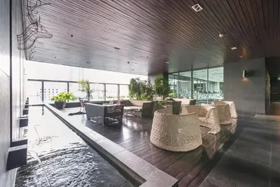 a lobby with a pool and tables and chairs at Noble Remix Thong Lo Long Stay Cozy&Warm Direct access to BTS Pool Gym WiFi in Bangkok