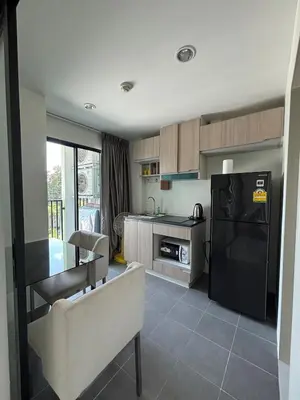 a kitchen with a black refrigerator and a table at Sukhumvit 50 apartment in Bangkok