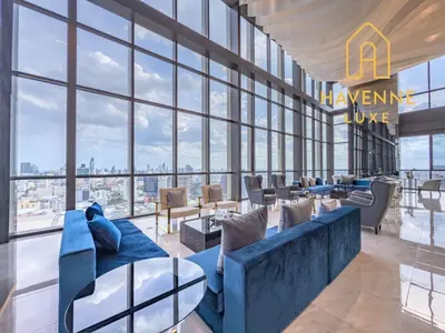 a living room with a blue couch and large windows at Luxury Downtown Bangkok 2BR 2BA Sky Pool Gym 5MIN Walk to Siam Paragon in Bangkok