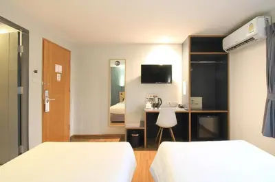 a hotel room with two beds and a desk at Mybed Sathorn Hotel in Bangkok