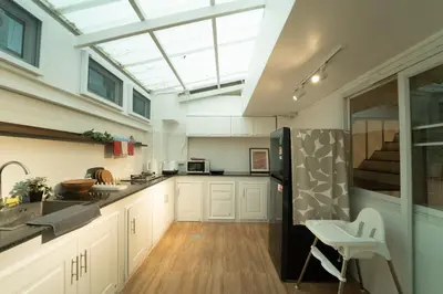 a kitchen with white cabinets and a black refrigerator at Roni House Thonglor in Bangkok