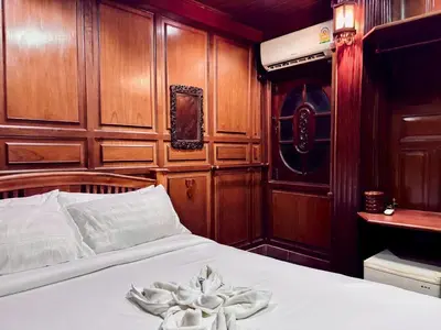 a bed in a room with wood paneled walls at Sukhum Ban Songthai in Bangkok
