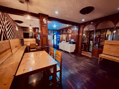 a restaurant with a wooden table and chairs in it at Sukhum Ban Songthai in Bangkok