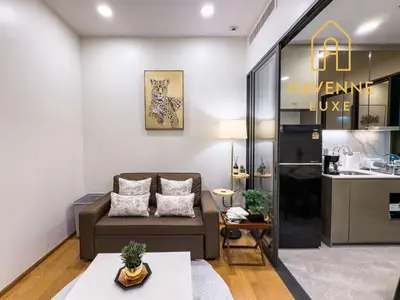 a living room with a couch and a kitchen at City Luxe Condo 5-Min Walk to Siam Paragon Modern Stay in Bangkok