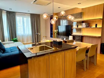 a kitchen with a sink and a living room at The Prestige Living Bangkok at Sathorn-Chan in Bangkok