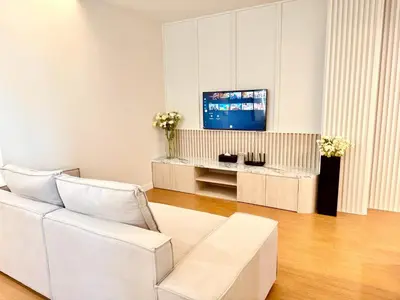 a living room with a white couch and a tv at The Prestige Living Bangkok at Sathorn-Chan in Bangkok