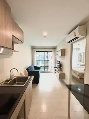 a kitchen with a sink and a living room at Bangkok apartment in Bangkok