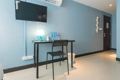 a table with a chair and a television in a room at The Little Pig Sukhumvit in Bangkok