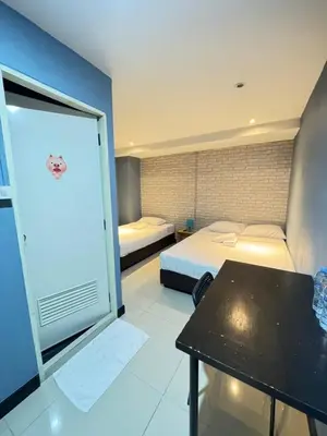 a small room with two beds and a table in it at The Little Pig Sukhumvit in Bangkok