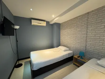 a bedroom with two beds and a brick wall at The Little Pig Sukhumvit in Bangkok