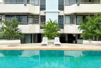 two chairs by a swimming pool in front of a building at New Renovated 2 Beds Amazing Balcony View Nana BTS in Bangkok