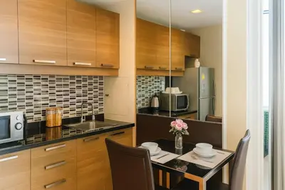 a kitchen with a table with chairs and a microwave at Cozy Urban Retreat in Sukhumvit Steps to BTS Nana in Bangkok