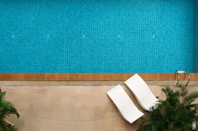 two white chairs sitting next to a swimming pool at Cozy Urban Retreat in Sukhumvit Steps to BTS Nana in Bangkok