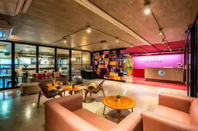 a lobby with tables and chairs and a store at De Botan Srinakarin Hotel & Residence in Bangkok