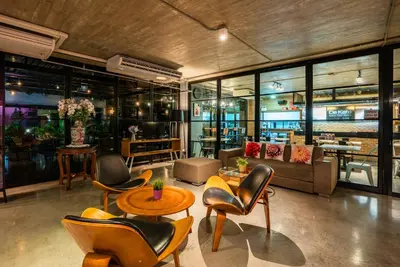 a lobby with chairs and tables and a couch at De Botan Srinakarin Hotel & Residence in Bangkok