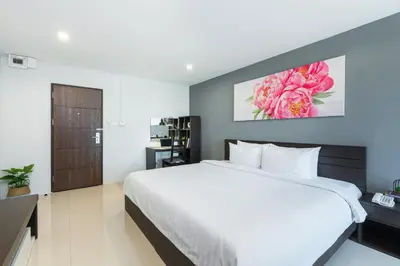 a bedroom with a large white bed and a desk at De Botan Srinakarin Hotel & Residence in Bangkok