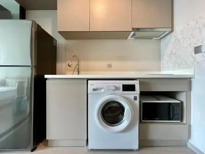 a kitchen with a washing machine under a counter at 1 bedroom Life Ladprao in Bangkok