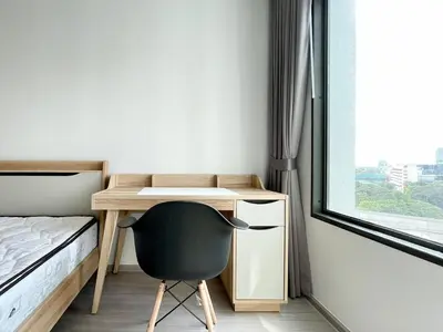 a bedroom with a desk and a chair next to a window at 1 bedroom Life Ladprao in Bangkok