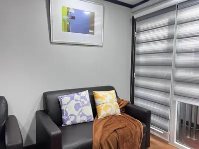 a living room with a black leather couch and a window at Sukhumvit soi 4 Apartment Center of BKK in Bangkok