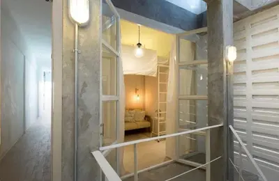 a glass shower in a room with a couch at TWH Hostel Bangkok in Bangkok