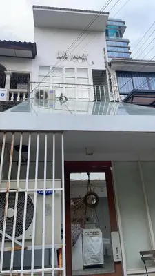 a white building with a balcony and a door at TWH Hostel Bangkok in Bangkok