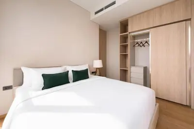 a bedroom with a large white bed with green pillows at Urban Oasis BTS Ekkamai in Khlong Toei