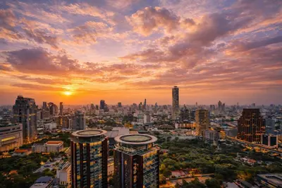 a city skyline at sunset with the sun setting at New City Condo in Central Bangkok in Pratunam
