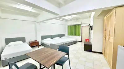 a room with two beds and a table and chairs at Bangkok-Pratunam Hotel in Bangkok