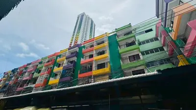 a building covered in colorful paint with a tall building at Bangkok-Pratunam Hotel in Bangkok