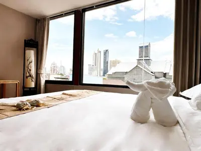 a white stuffed elephant sitting on a bed in front of a window at Chinatown No9 Boutique Hotel in Bangkok