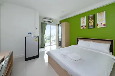 a green bedroom with a bed with two towels on it at B32 Apartment in Bangna