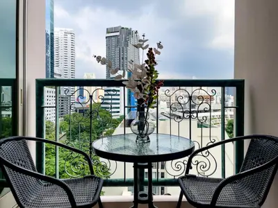 a table with chairs and a vase with flowers on a balcony at 300m BTS l Large 110 sqm l Pool and Sauna in Bangkok