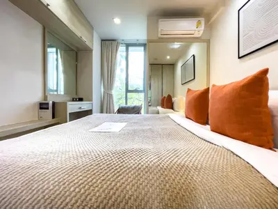 a bedroom with a large bed with orange pillows at Near BTS Asok and MRT SKV l Pool and Sauna in Bangkok