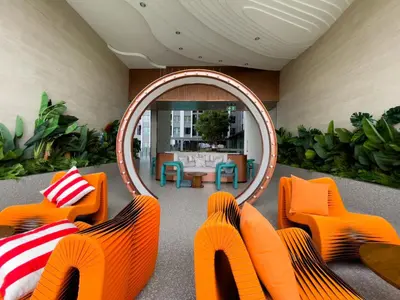a living room with orange chairs and a mirror at 600 m to BTS l City View l Rooftop Pool in Bangkok