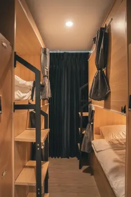 a small room with a bed and a bunk bed with bags at Greet Hostel & Cafe Samyan in Bangkok