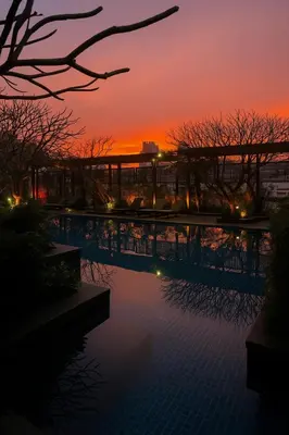 a sunset over a swimming pool at a resort at Cozy High-Rise Escape in the heart of Bangkok! in Bangkok