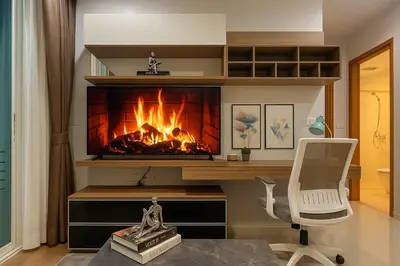 a fireplace in a living room with a white chair at Cozy High-Rise Escape in the heart of Bangkok! in Bangkok