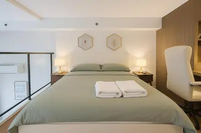 a bedroom with a large bed with two towels on it at Incredible Loft with High Ceiling in Bangkok