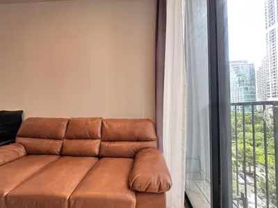 a brown couch in a room with a window at Noble Bangkok Condo in Bangkok