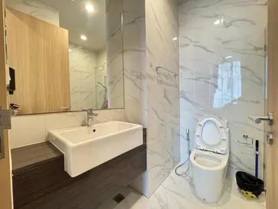 a white bathroom with a sink and a toilet at Noble Bangkok Condo in Bangkok
