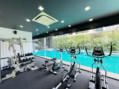 a gym with cardio machines and a swimming pool at Ekkamai Bangkok Condo in Bangkok
