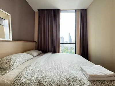 a bedroom with a large bed with a window at Ekkamai Bangkok Condo in Bangkok