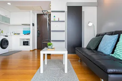 a living room with a black couch and a white table at Warm&Cozy Stay near BTS Thonglor in Bangkok