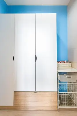 a closet with white cabinets and a blue wall at Warm&Cozy Stay near BTS Thonglor in Bangkok
